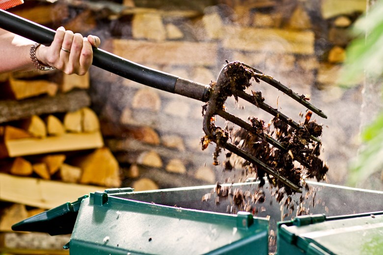 A garden fork is used to stir the contents of compost.
