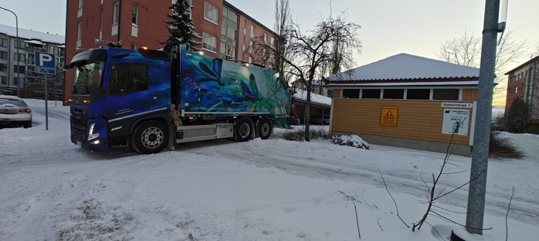 HSY:n jäteauto kerrostalon jätetilan edessä.