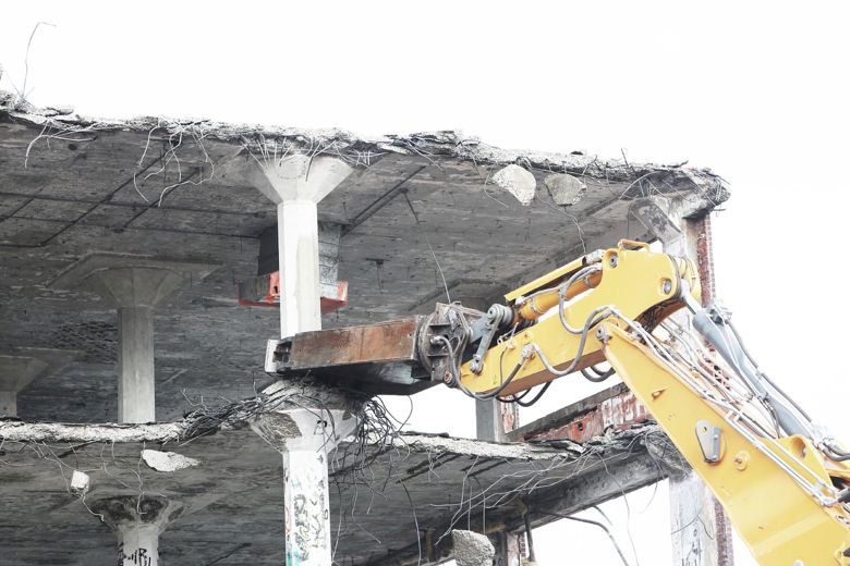 Kuvituskuva. Rakennuksen betoniosia irrotetaan työkoneella.