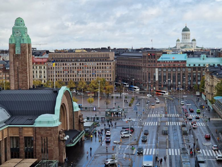 Helsingin rautatieaseman edustalla kulkee autoja ja taustalla siintää tuomiokirkko.