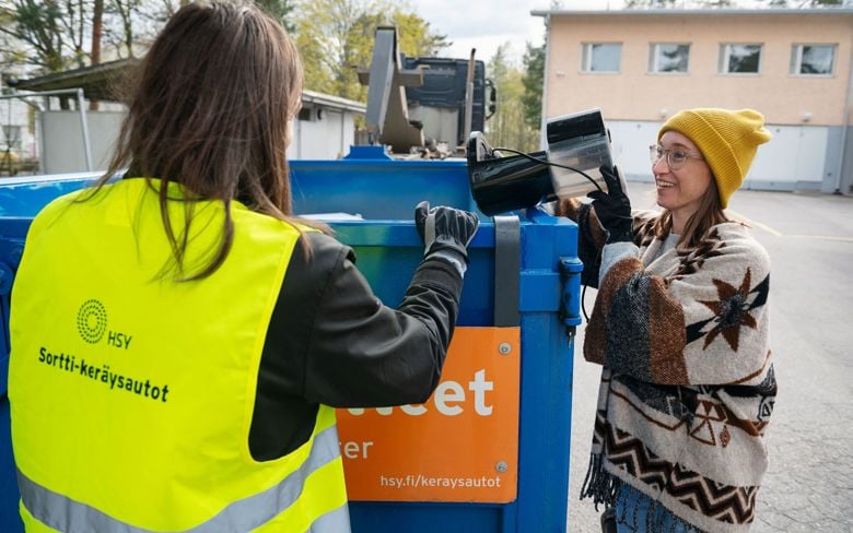 Henkilökunta opastaa asiakasta, joka tuo rikkimenneen sähkölaitteen Sortti-keräysautokierrokselle.