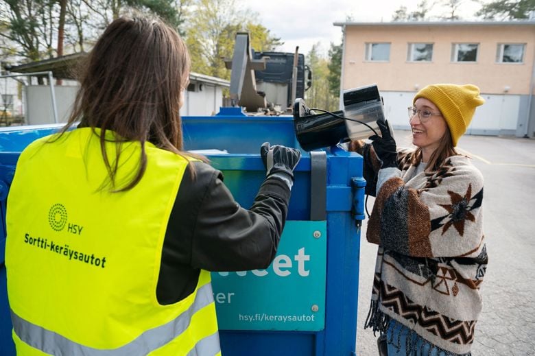 Henkilökunta opastaa asiakasta, joka tuo rikkimenneen sähkölaitteen Sortti-keräysautokierrokselle.