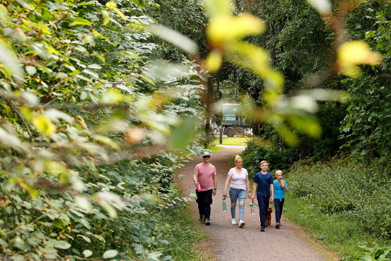 Kaksi aikuista ja kaksi lasta kävelevät polkua pitkin metsässä.