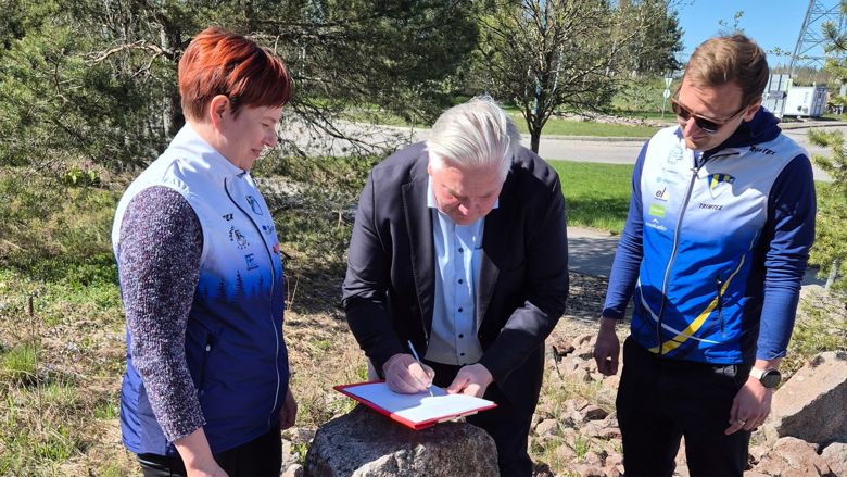 Kolme henkilöä allekirjoittavat Jukolan viestin sopimuksen.