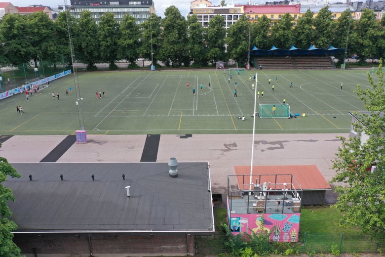 Jalkapallokentän läheisyydessä seisoo ilmanlaadun mittausasema, jonka seinässä on maalaus.