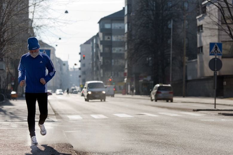 Pölyltä suojautuva lenkkeilijä katuympäristössä