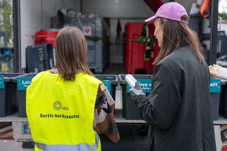 Sortti-keräysauton työntekijä auttaa asukasta lajittelemaan vaaralliset jätteen oikeisiin keräysastioihin.
