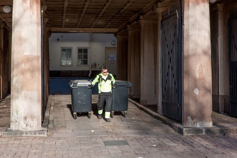 Henkilö kävelee pois jätetilasta ja vetää perässään kahta jäteastiaa.