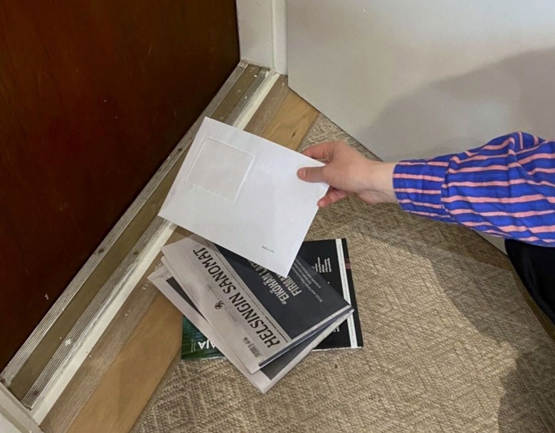 Lattialla näkyy postiluukusta tullutta paperipostia. 