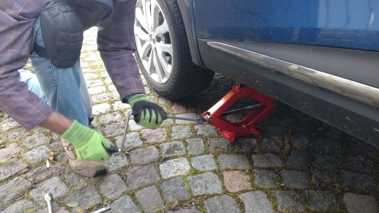 Henkilö vaihtaa renkaita autoon.