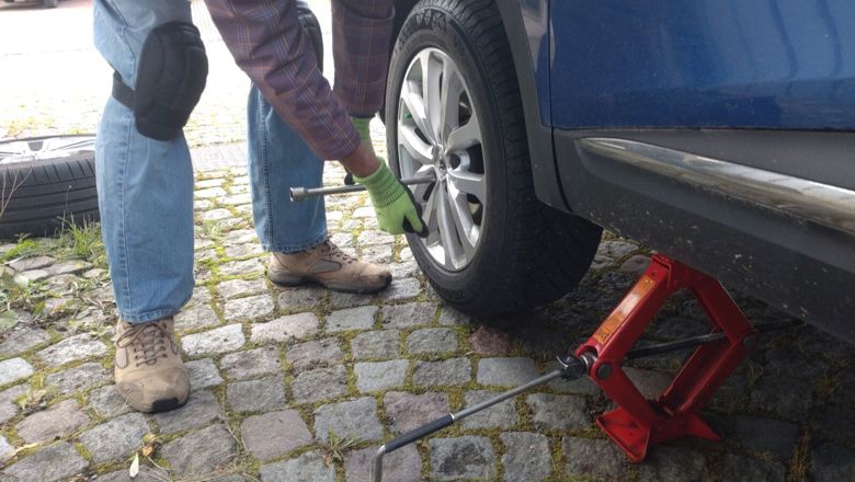 Henkilö vaihtaa rengasta autoon.