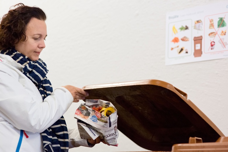 Nainen laittaa biojätepussia biojäteastiaan.