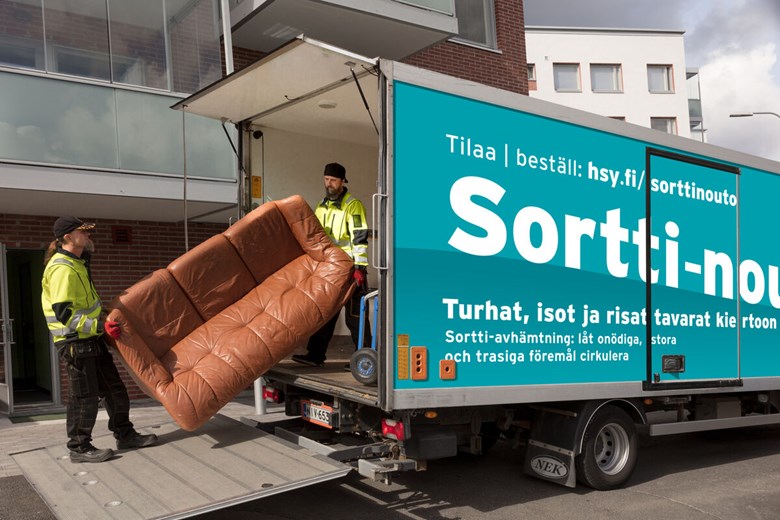 Two people carry a couch into a lorry.