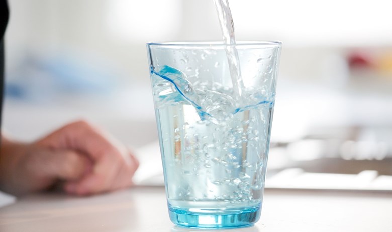 Kirkkaaseen juomalasiin kaadetaan vettä.